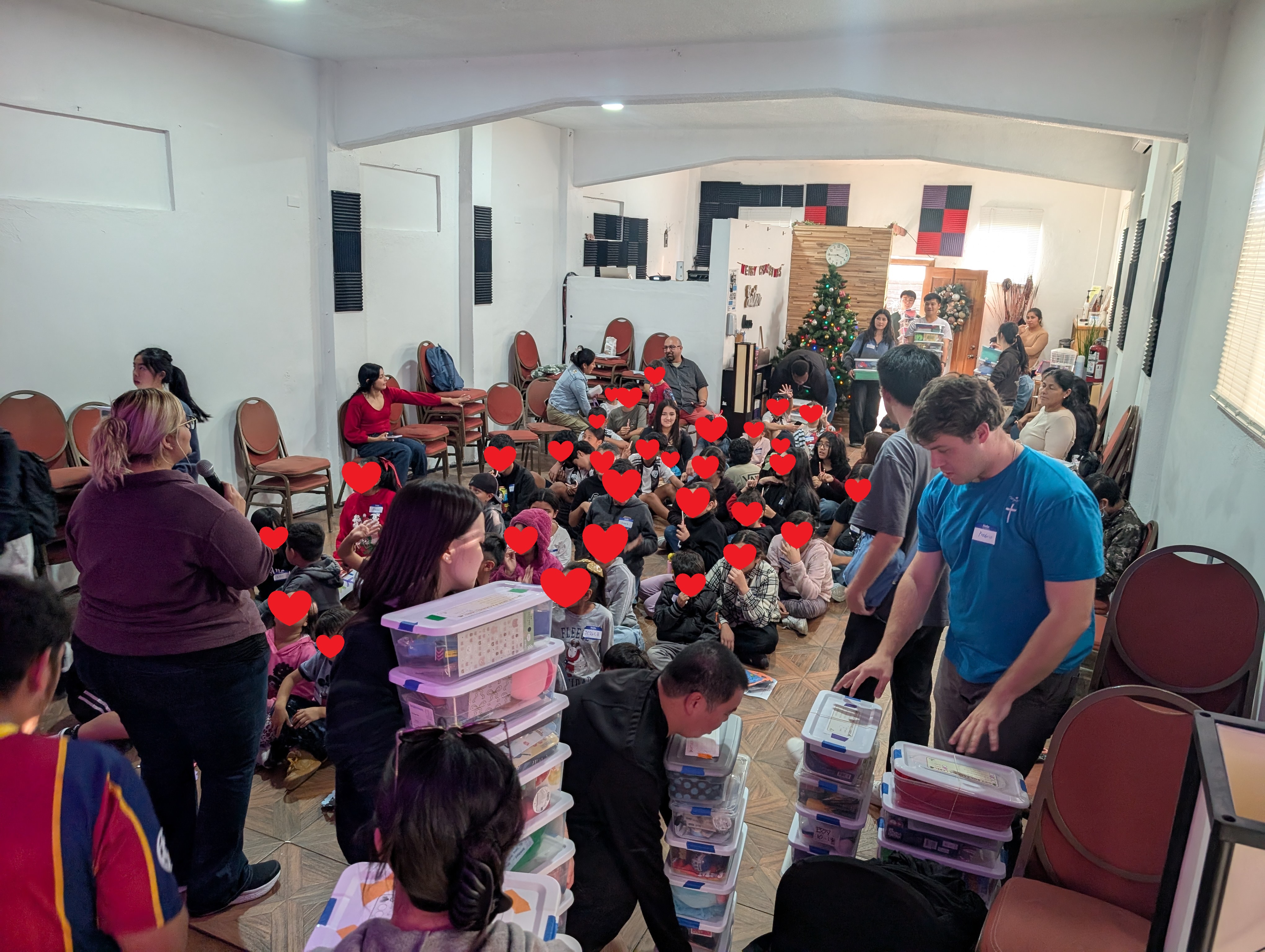 Renewal Missions volunteers delivering stacks of Christmas gift boxes to kids gathered at Parousia during the Tijuana day trip